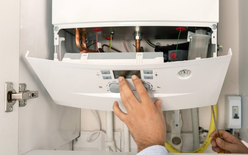 Técnico manipulando el panel de control de una caldera de gas con el frontal abierto